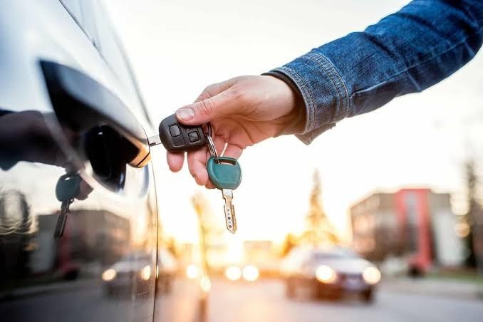 Hand holding car keys next to a car door in Sacramento
