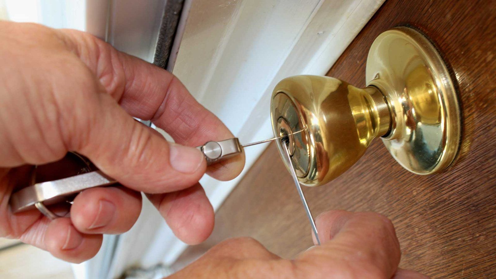 Locksmith picking a brass doorknob lock on a Sacramento home