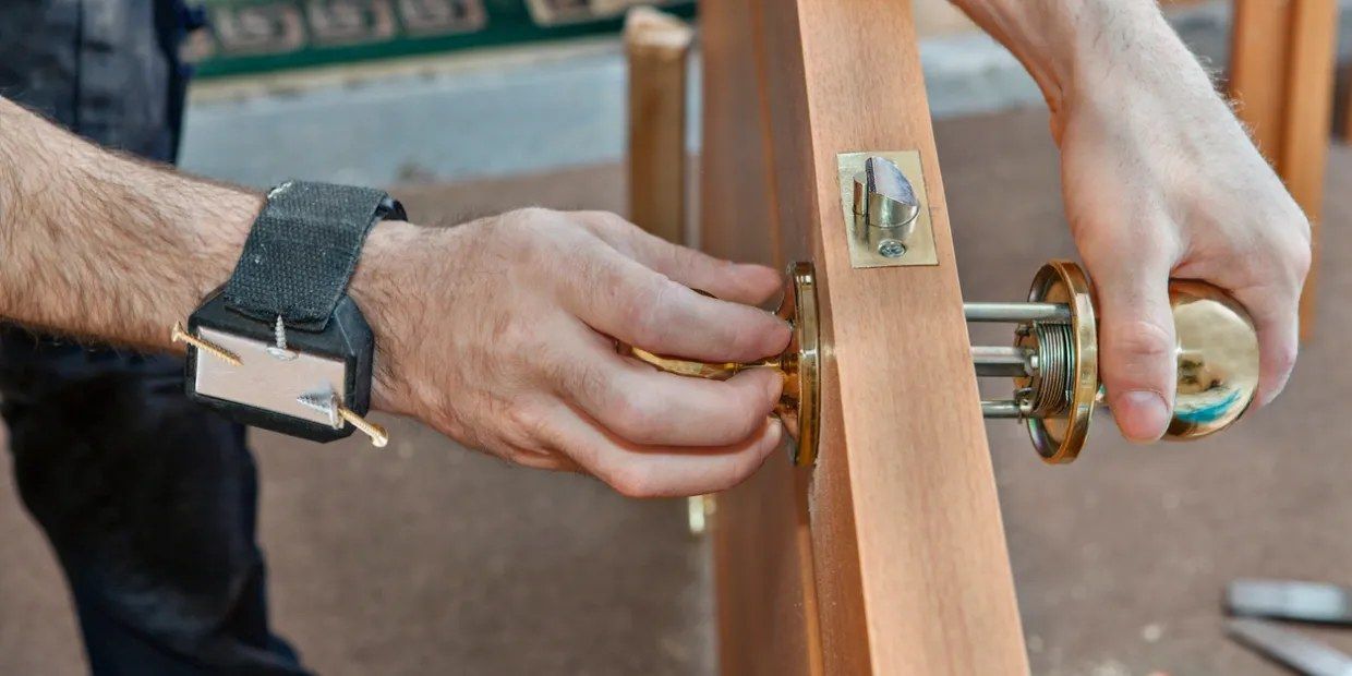 Hands installing a brass doorknob on a wooden door in Sacramento