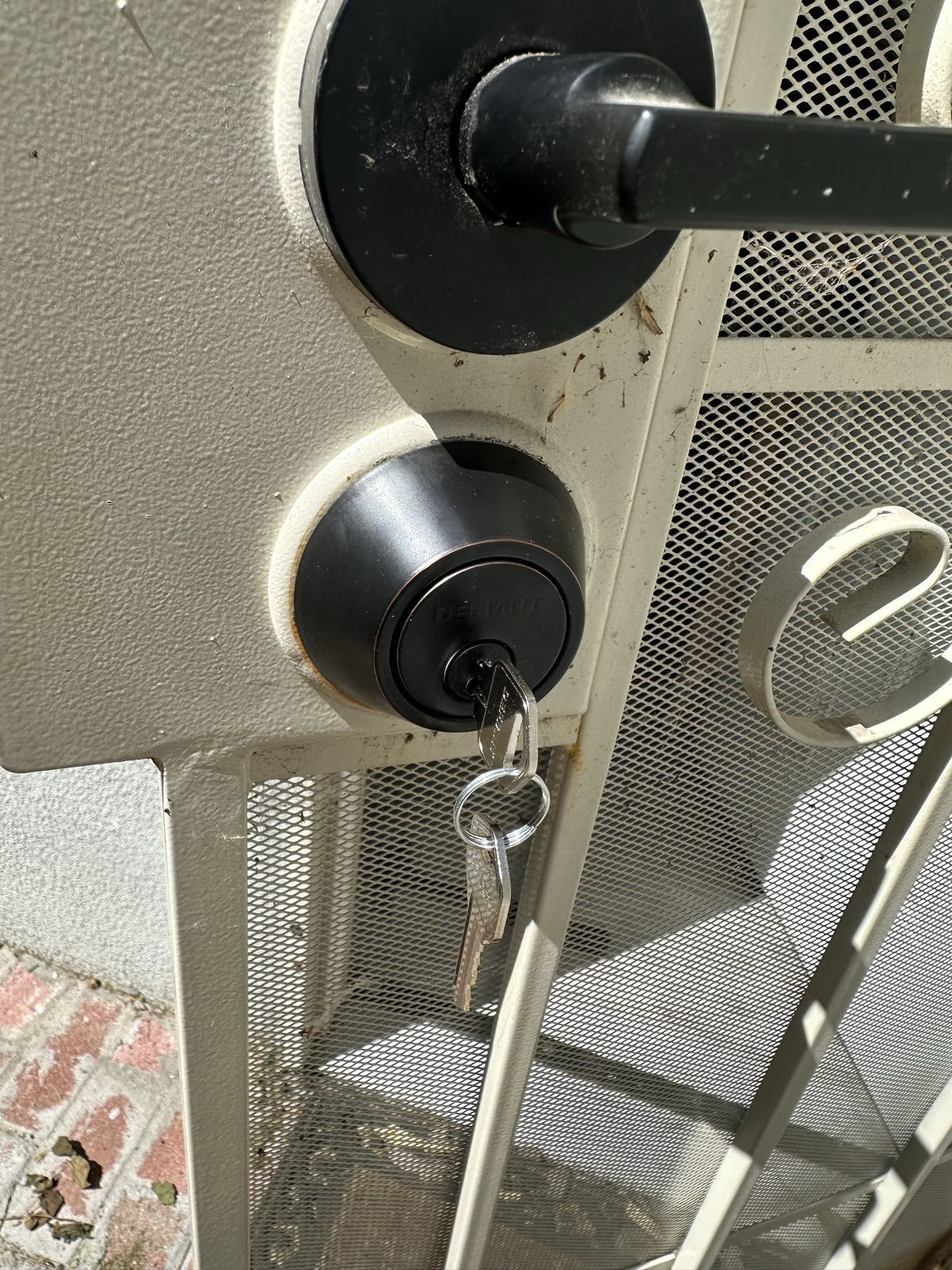 Key in a black deadbolt on a security screen door in Sacramento