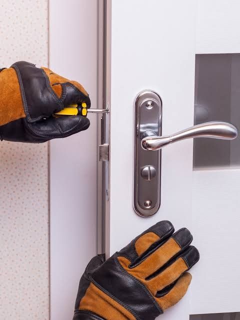 Locksmith in work gloves repairing a door lever lock in Sacramento